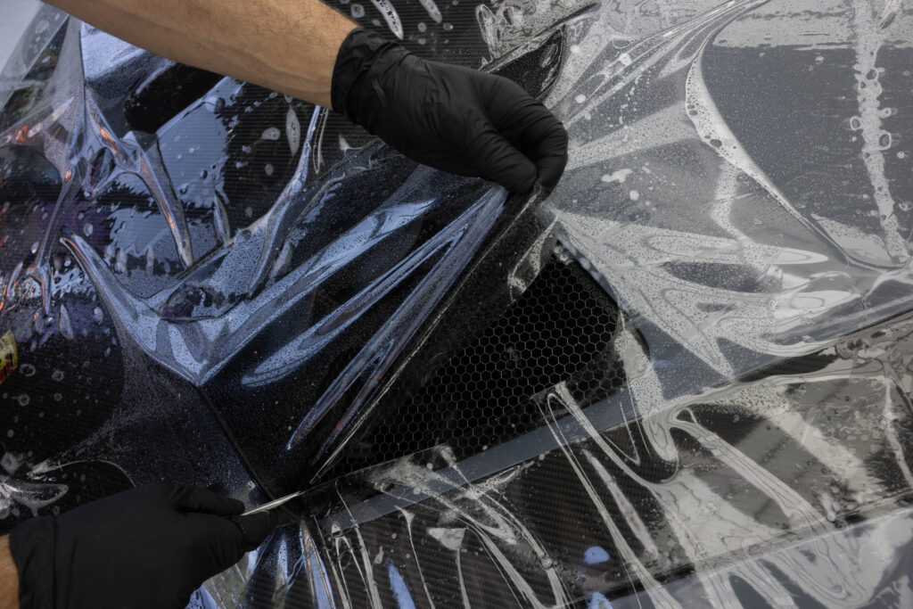 Aufziehen von PPF Schutzfolie auf Motorhaube von grauem Porsche GT3 RS