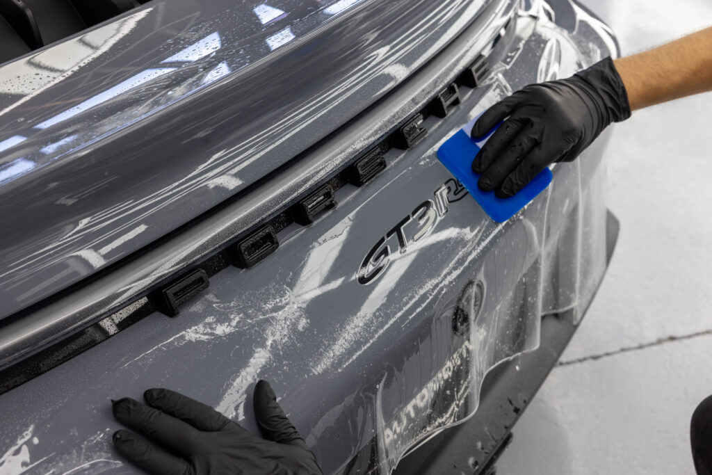 Aufziehen von PPF Schutzfolie auf Heck von grauem Porsche GT3 RS